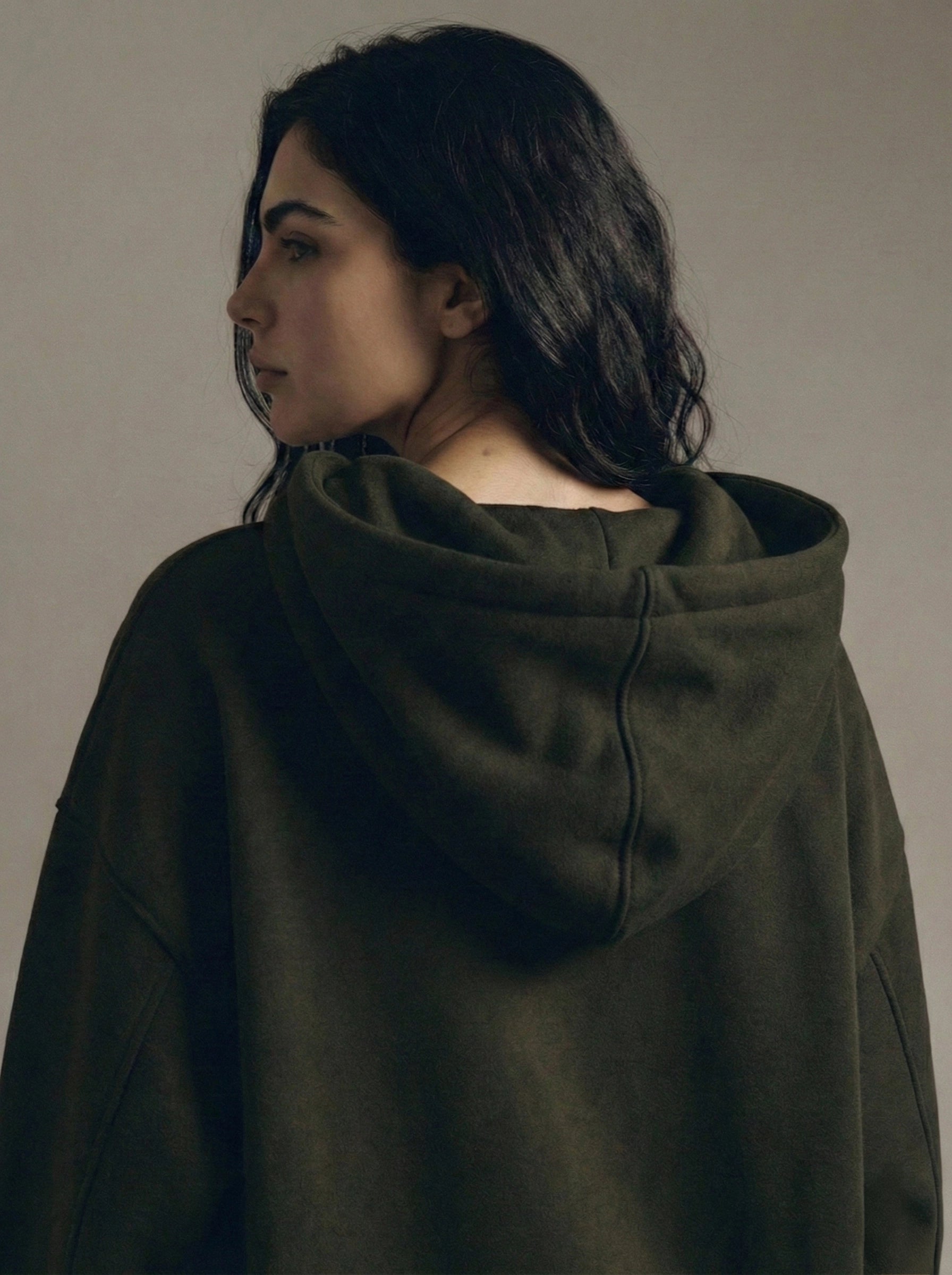 Person wearing a dark green hoodie against a plain background