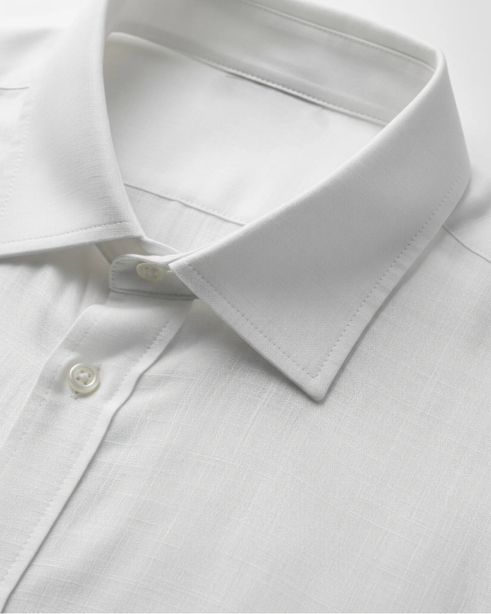 Close-up of a white dress shirt with a collar and button